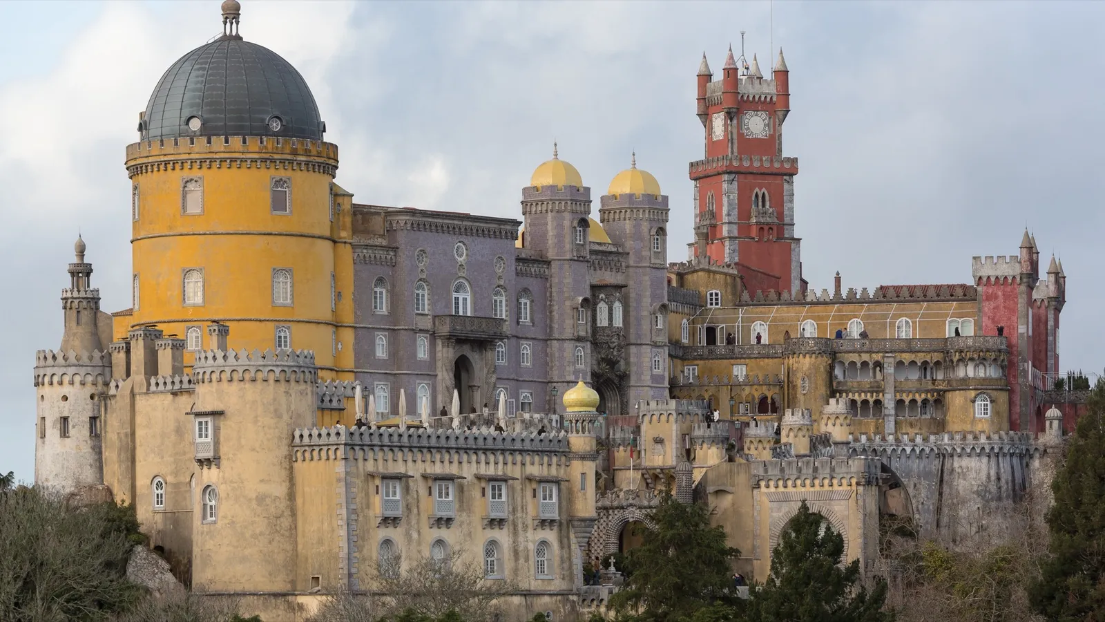 Pena Palace's colorful towers and clock tower rising above Sintra, Portugal