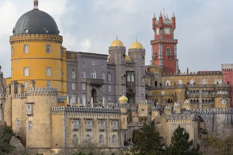Pena Palace's colorful towers and clock tower rising above Sintra, Portugal