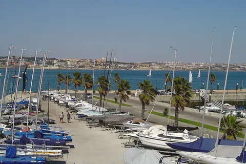 Marina in Cascais, Portugal, with sailboats, palm trees and the town across the bay