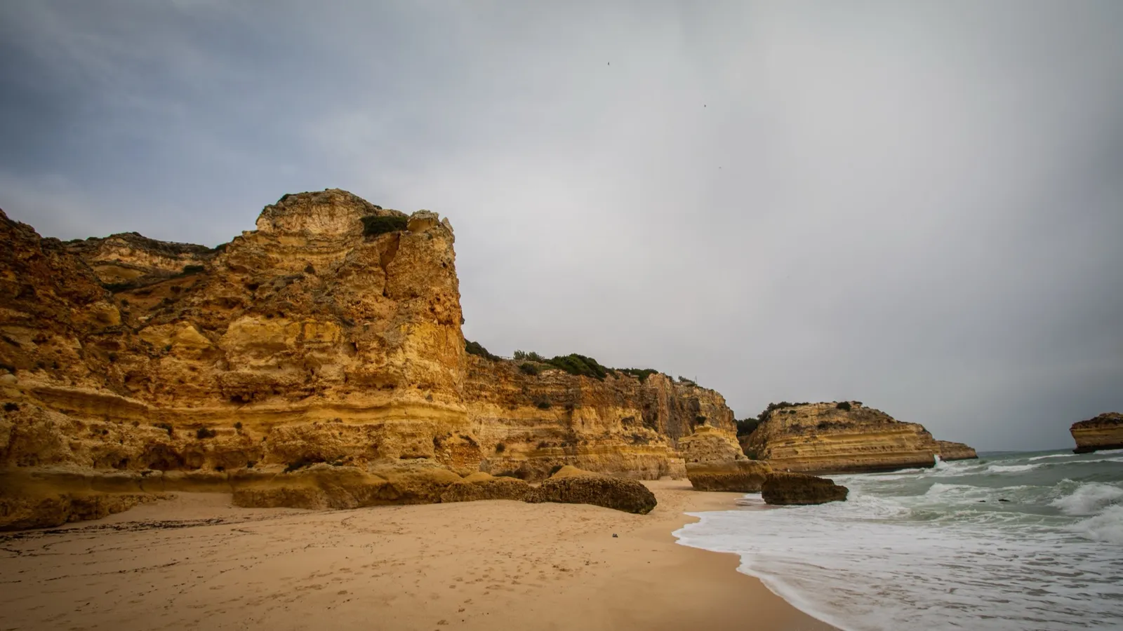 Weathered golden sandstone cliffs and a quiet cove beach on the Algarve coast in Portugal in July