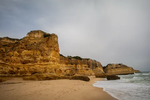 Weathered golden sandstone cliffs and a quiet cove beach on the Algarve coast in Portugal in July
