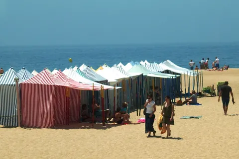 Traditional striped beach tents on a sandy Portuguese beach in summer
