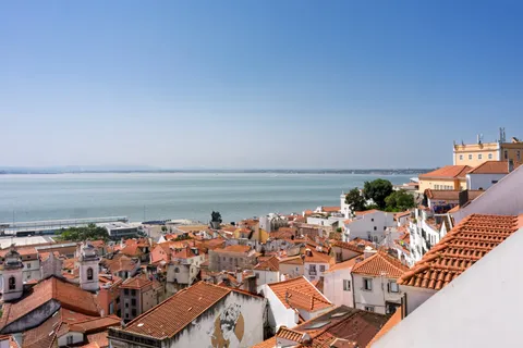 Toits de tuiles de l'Alfama à Lisbonne surplombant le Tage, le Portugal du quotidien derrière le débat avantages-inconvénients