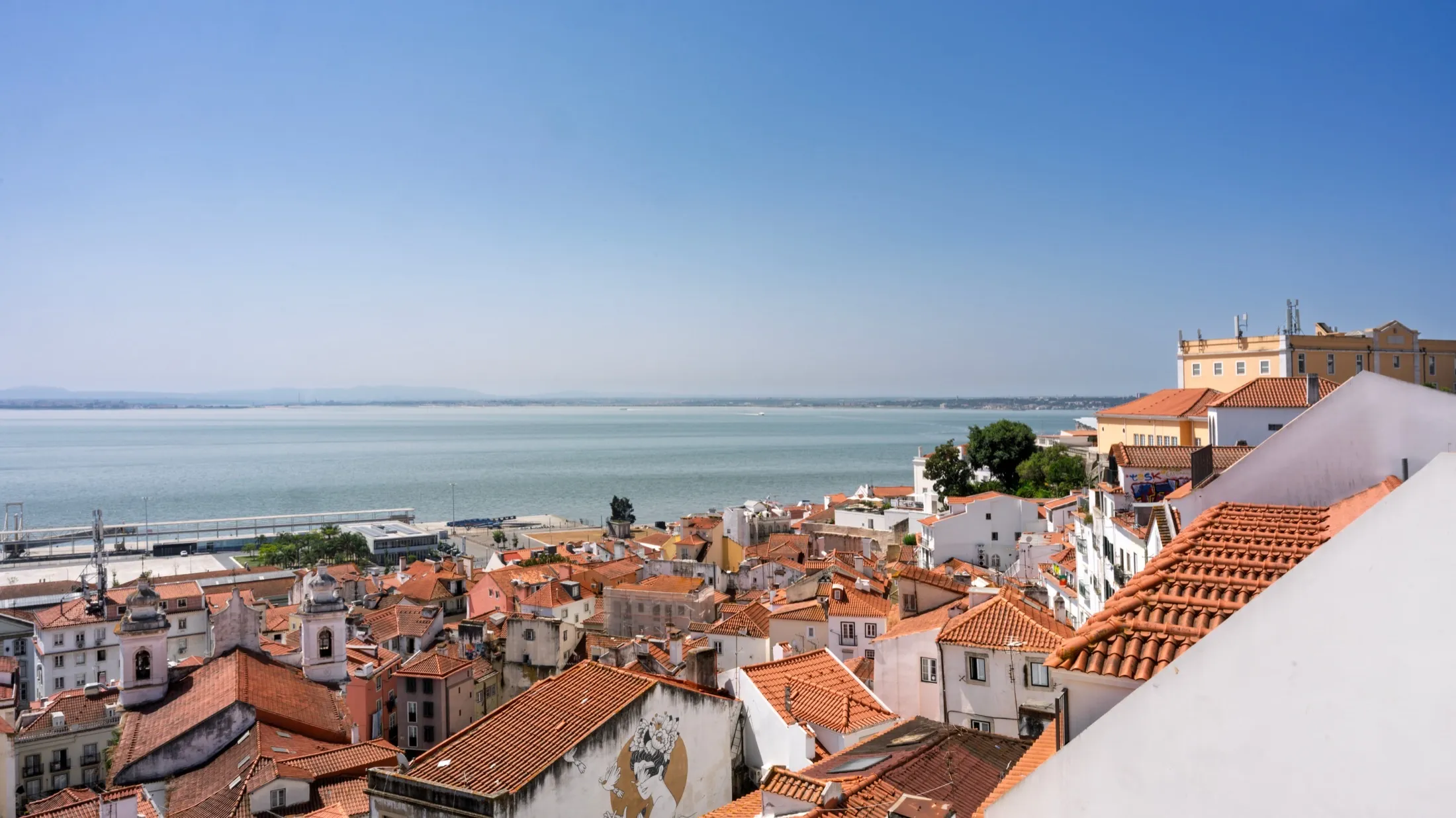 Toits de tuiles de l'Alfama à Lisbonne surplombant le Tage, le Portugal du quotidien derrière le débat avantages-inconvénients