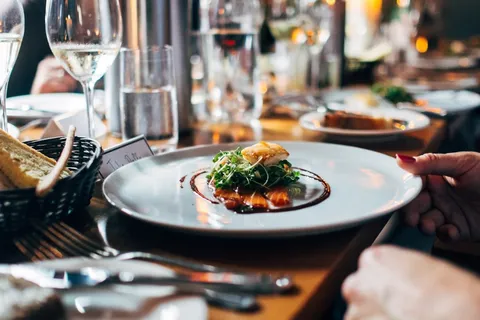 Mesa de restaurante elegante con comida y copas de vino, ilustrando la guía de propinas en Portugal