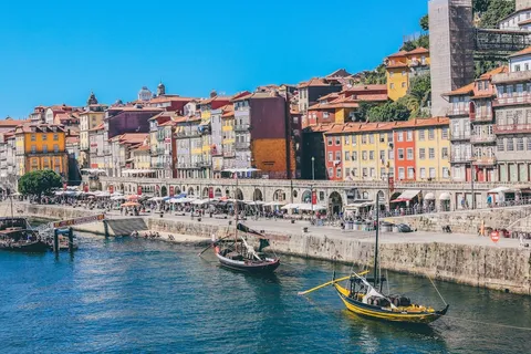 Sunny September afternoon on the Ribeira waterfront in Porto with rabelo boats on the Douro and riverside cafe terraces