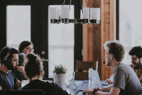 Trabajadores remotos con laptops en una mesa compartida de un coworking en Lisboa