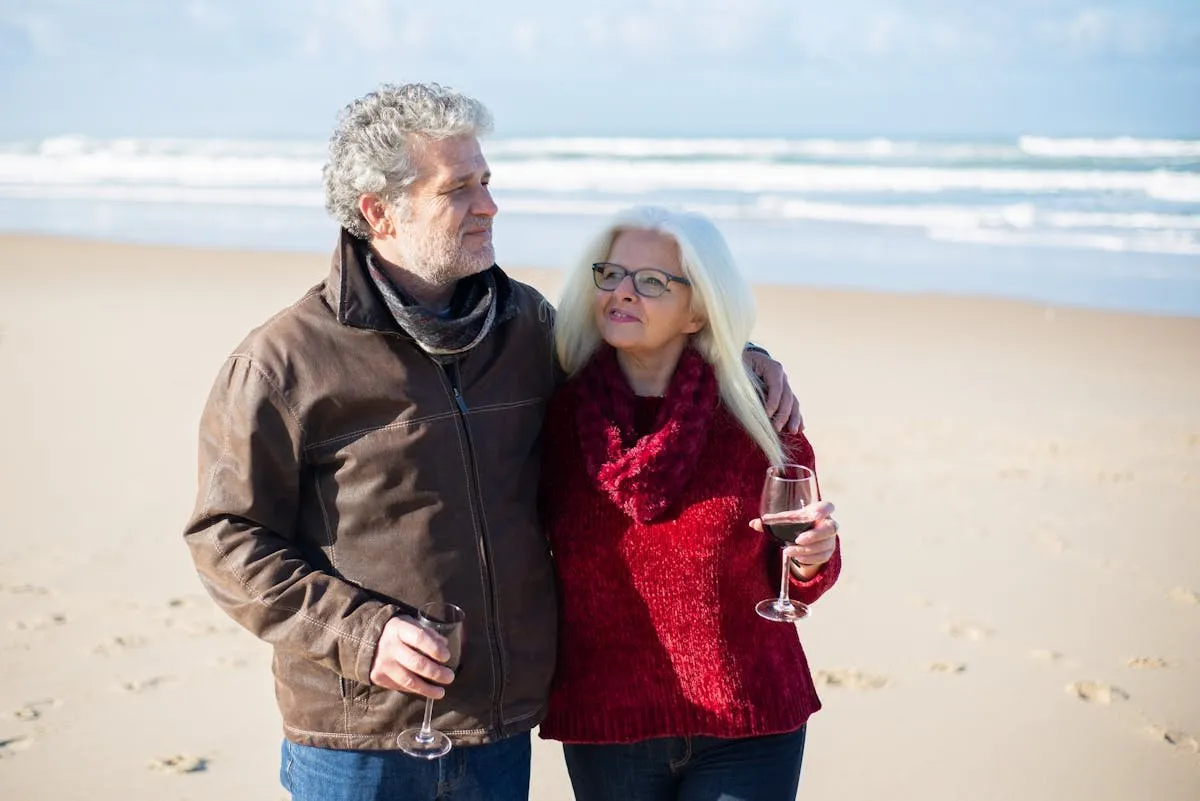 Couple de retraités dégustant du vin sur une plage atlantique — guide de la retraite au Portugal 2026