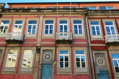 Tiled apartment façade with wrought-iron balconies on a residential street in Porto, Portugal