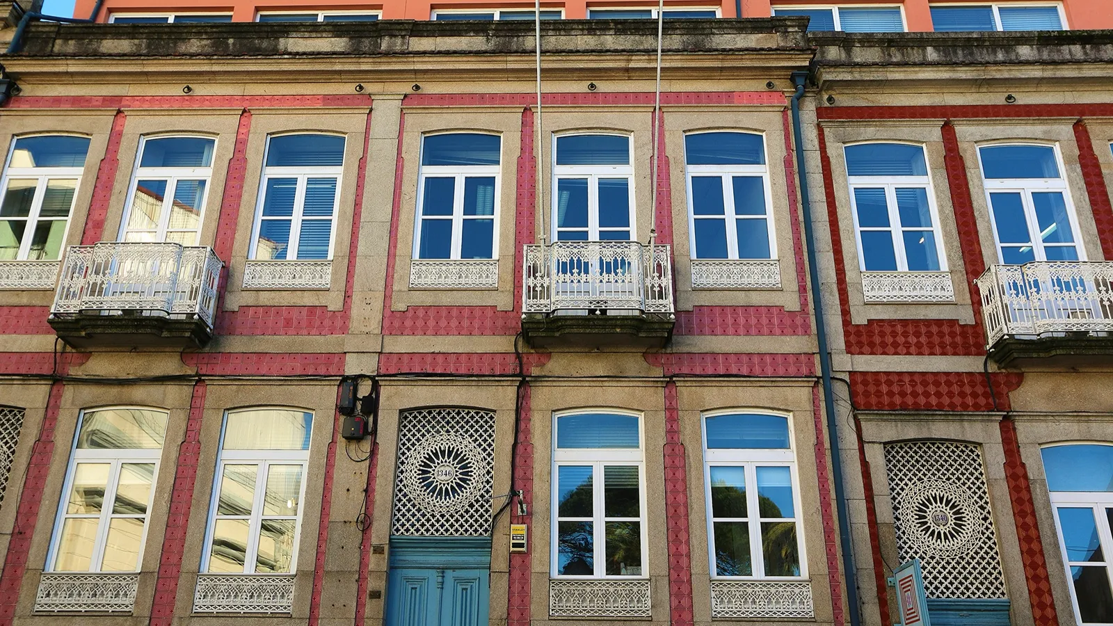 Tiled apartment façade with wrought-iron balconies on a residential street in Porto, Portugal