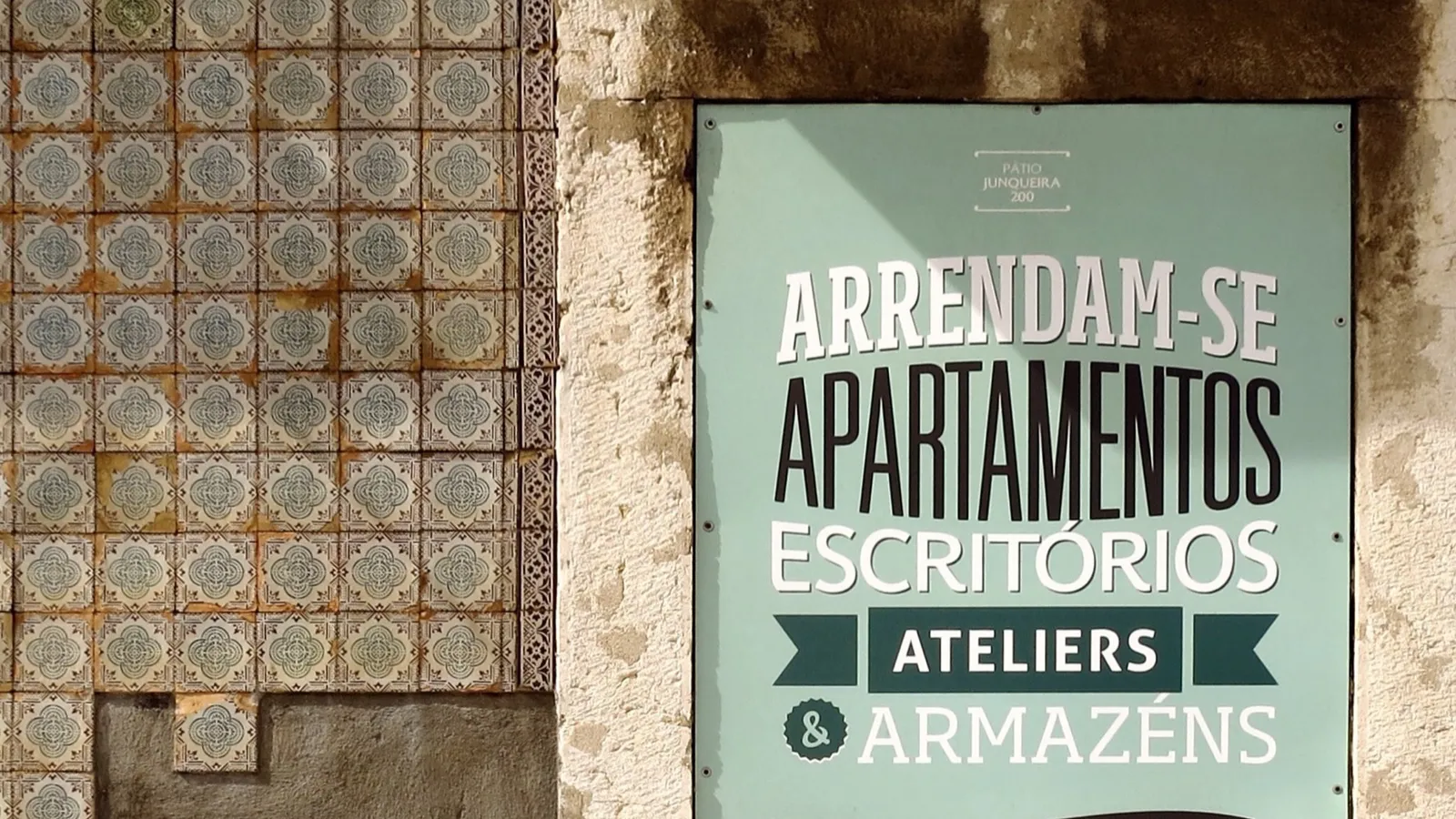 An "Arrendam-se apartamentos" for-rent sign on an azulejo-tiled wall in Lisbon; genuine listings like this are what rental scams in Portugal copy