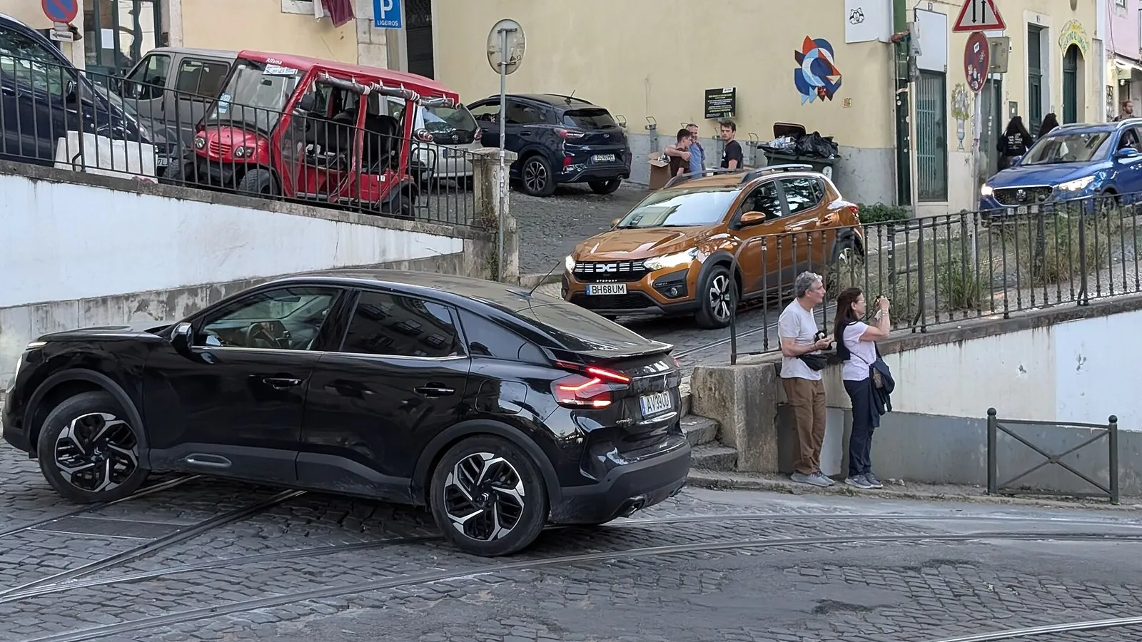 Autos estacionados en una calle empedrada de Lisboa con matrículas portuguesas, que ilustra la compra de un auto en Portugal