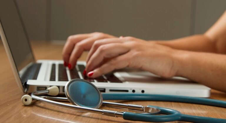 Stethoscope next to a laptop — comparing health insurance for expats in Portugal