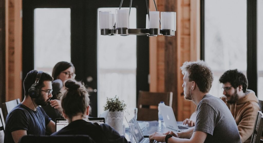 Remote workers with laptops at a shared table in a Lisbon coworking space