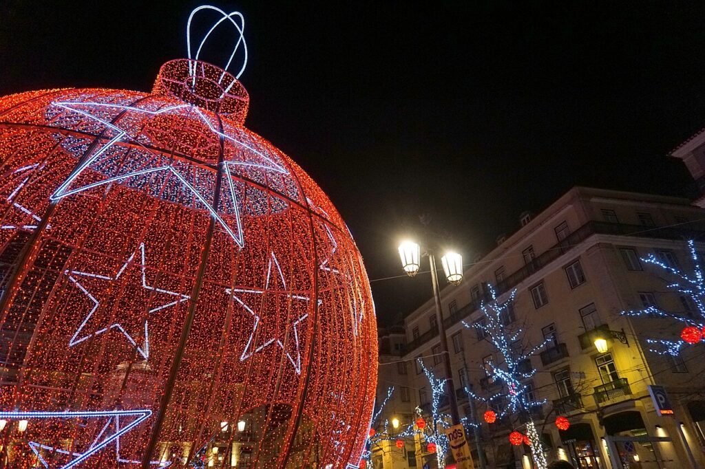 Giant illuminated red Christmas bauble lighting up a Lisbon street at night during the Portuguese holiday season