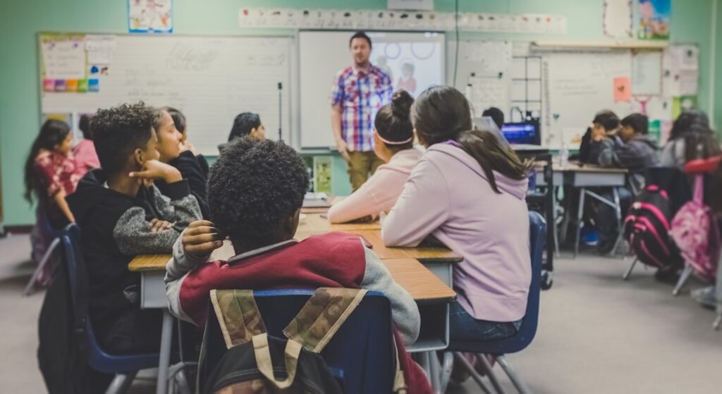 Diverse group of students at desks listening to a teacher in an international school classroom